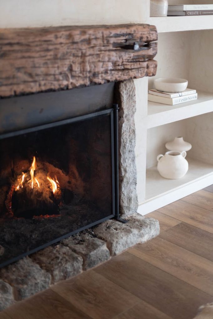 Warm and inviting fireplace with wooden mantel in a stylish living room setting, featuring modern decor.